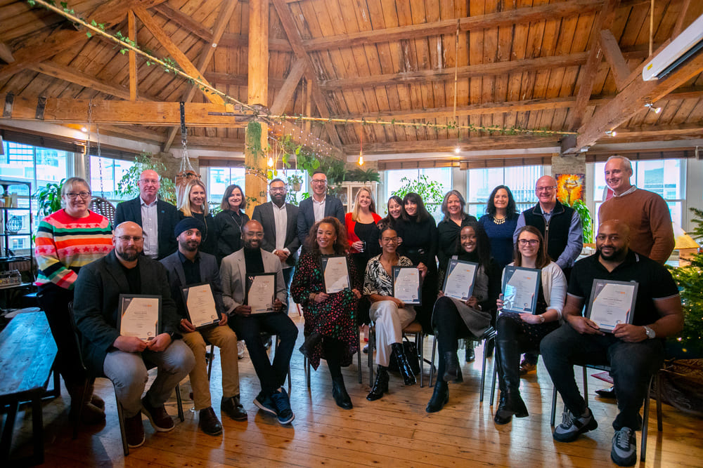 Group of DEI coaching students holding their awards and smiling